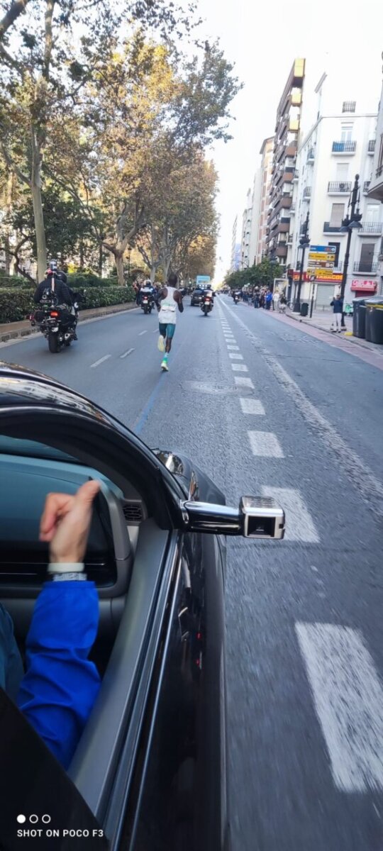 Corredor en el Maratón de Valencia 2025 con motos de seguridad