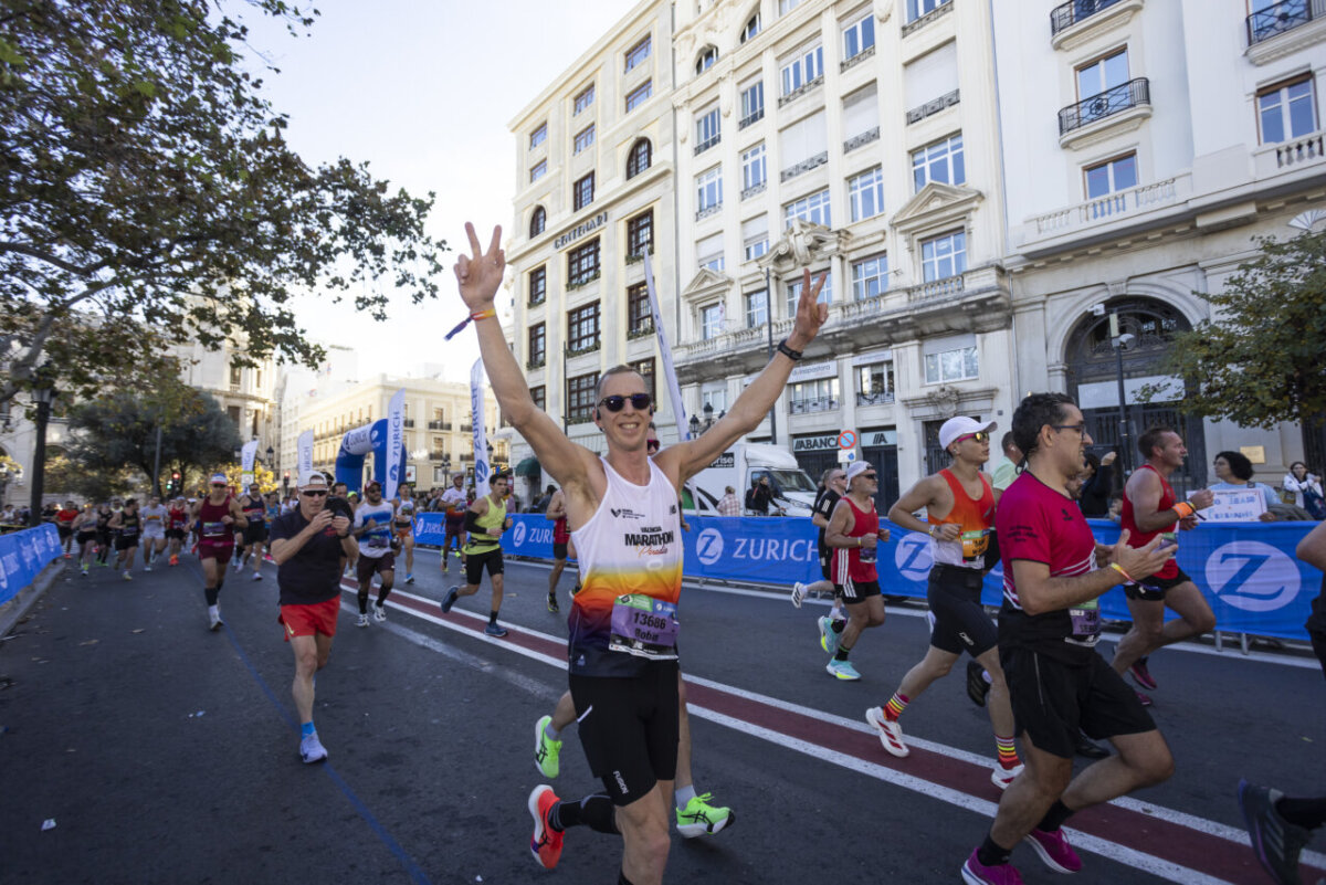 Corredores sonrientes durante el Maratón de Valencia 2025 en una calle vibrante.