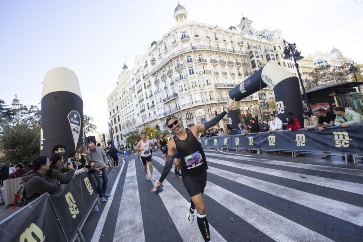 Corredor sonriente en el Maratón de Valencia 2025 con público animando.