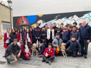 Grupo de estudiantes y artistas junto al mural homenaje a los perros de rescate