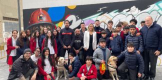 Grupo de estudiantes y artistas junto al mural homenaje a los perros de rescate