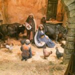 Escena de nacimiento con figuras de animales y pastores en un establo.