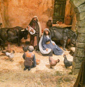 Escena de nacimiento con figuras de animales y pastores en un establo.