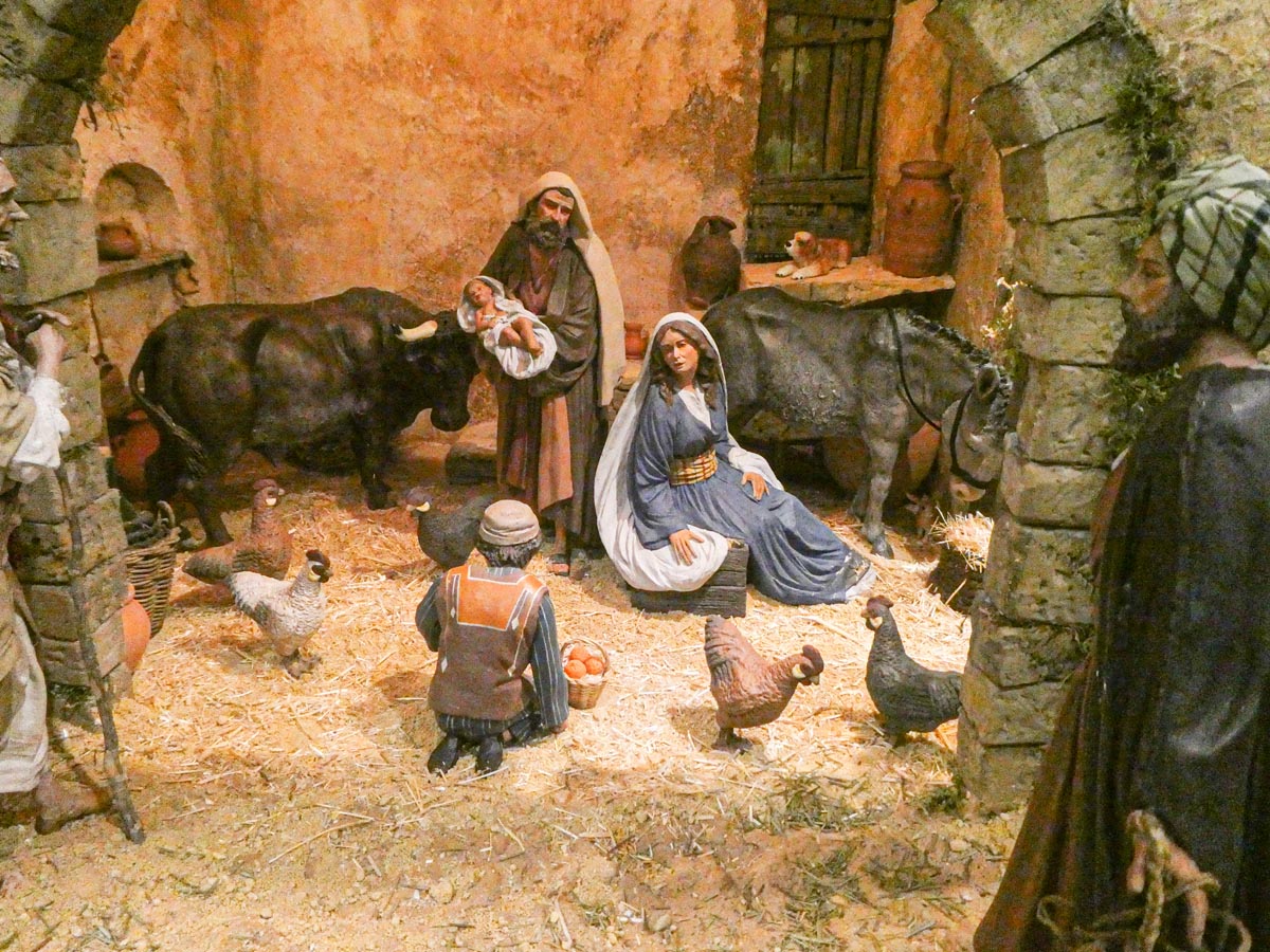 Escena de nacimiento con figuras de animales y pastores en un establo.