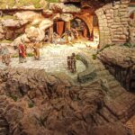 Escena de un nacimiento navideño con figuras artesanales en un paisaje rocoso.