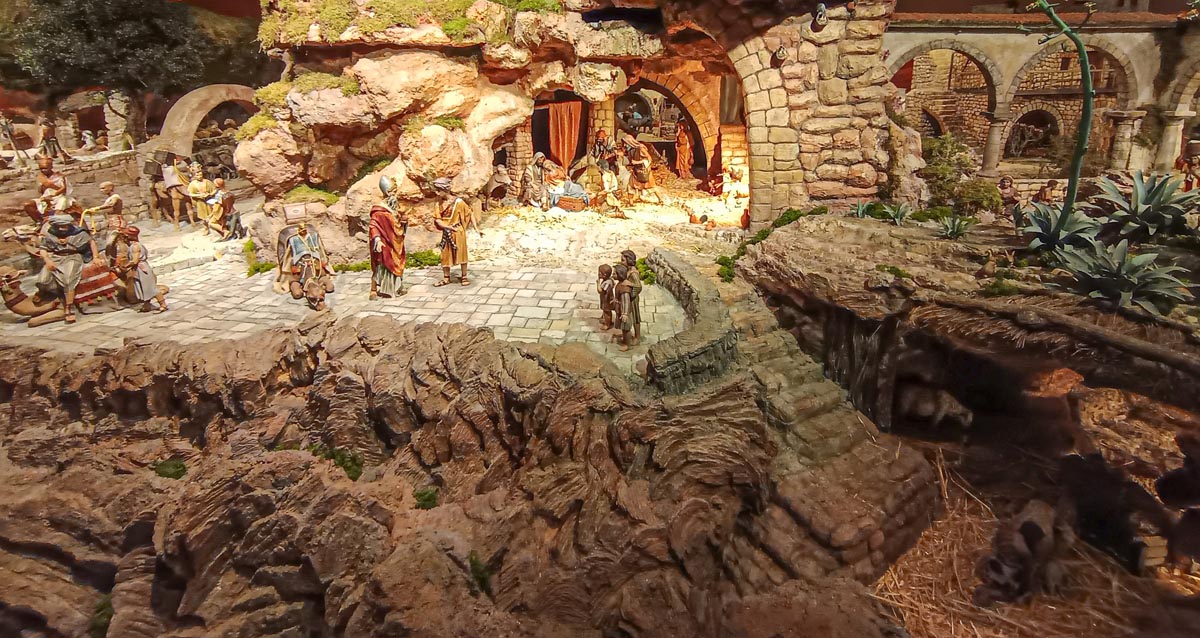 Escena de un nacimiento navideño con figuras artesanales en un paisaje rocoso.