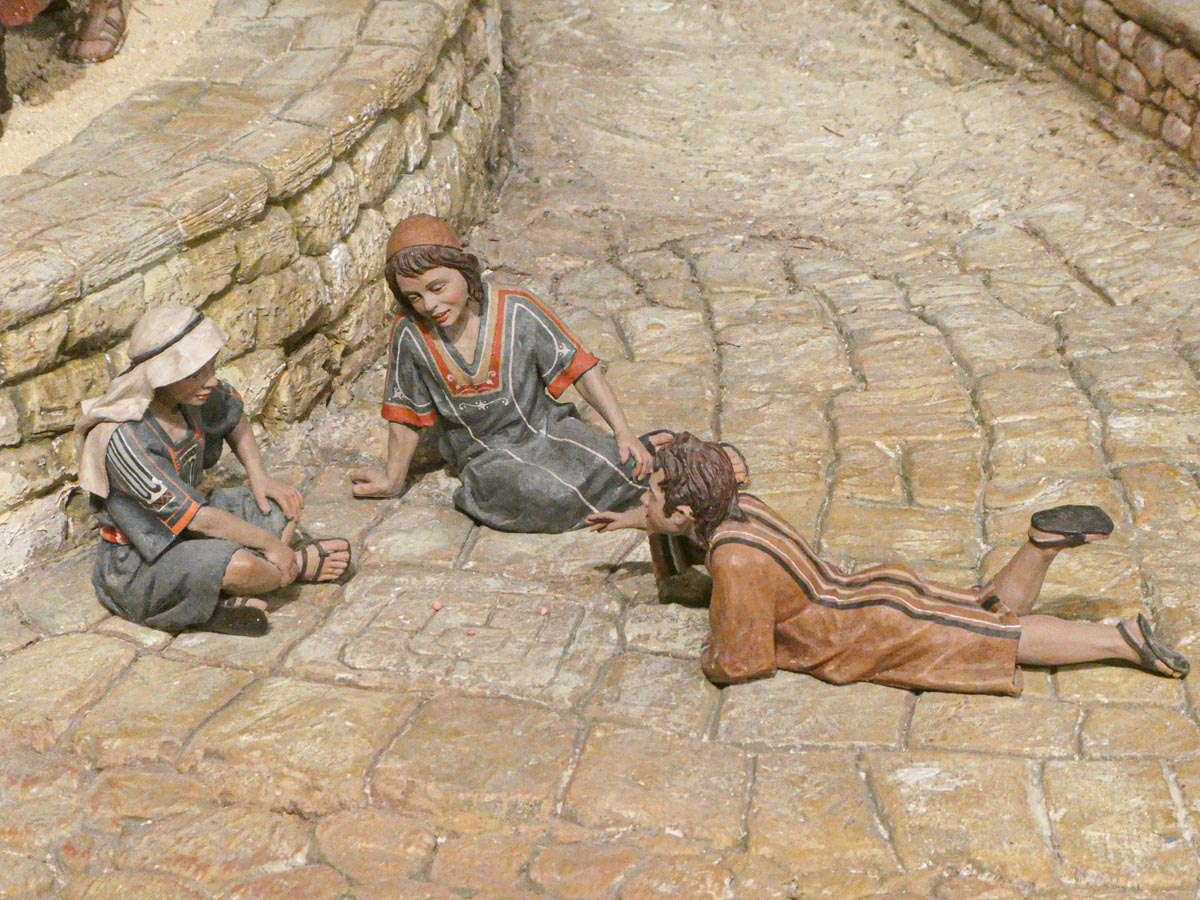 Tres figuras de niños jugando en una calle empedrada