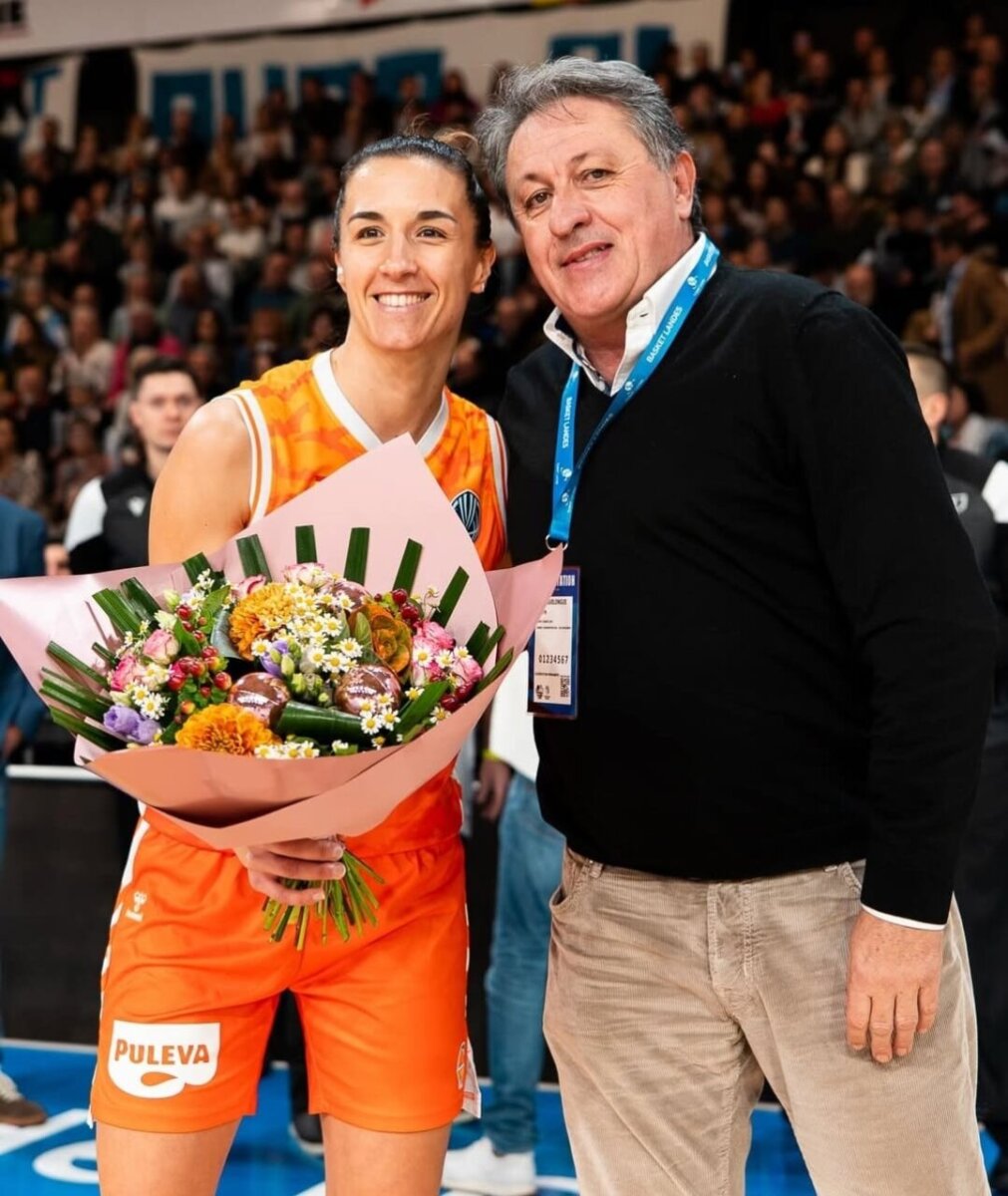 Jugadora de Valencia Basket con ramo de flores y un hombre sonriente