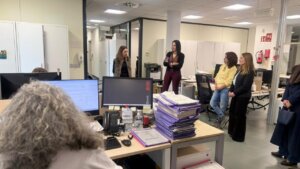 Reunión en oficina con varias mujeres conversando y trabajando.