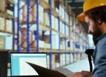 Operario revisando inventario en un almacén con sistema ERP
