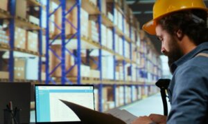 Operario revisando inventario en un almacén con sistema ERP
