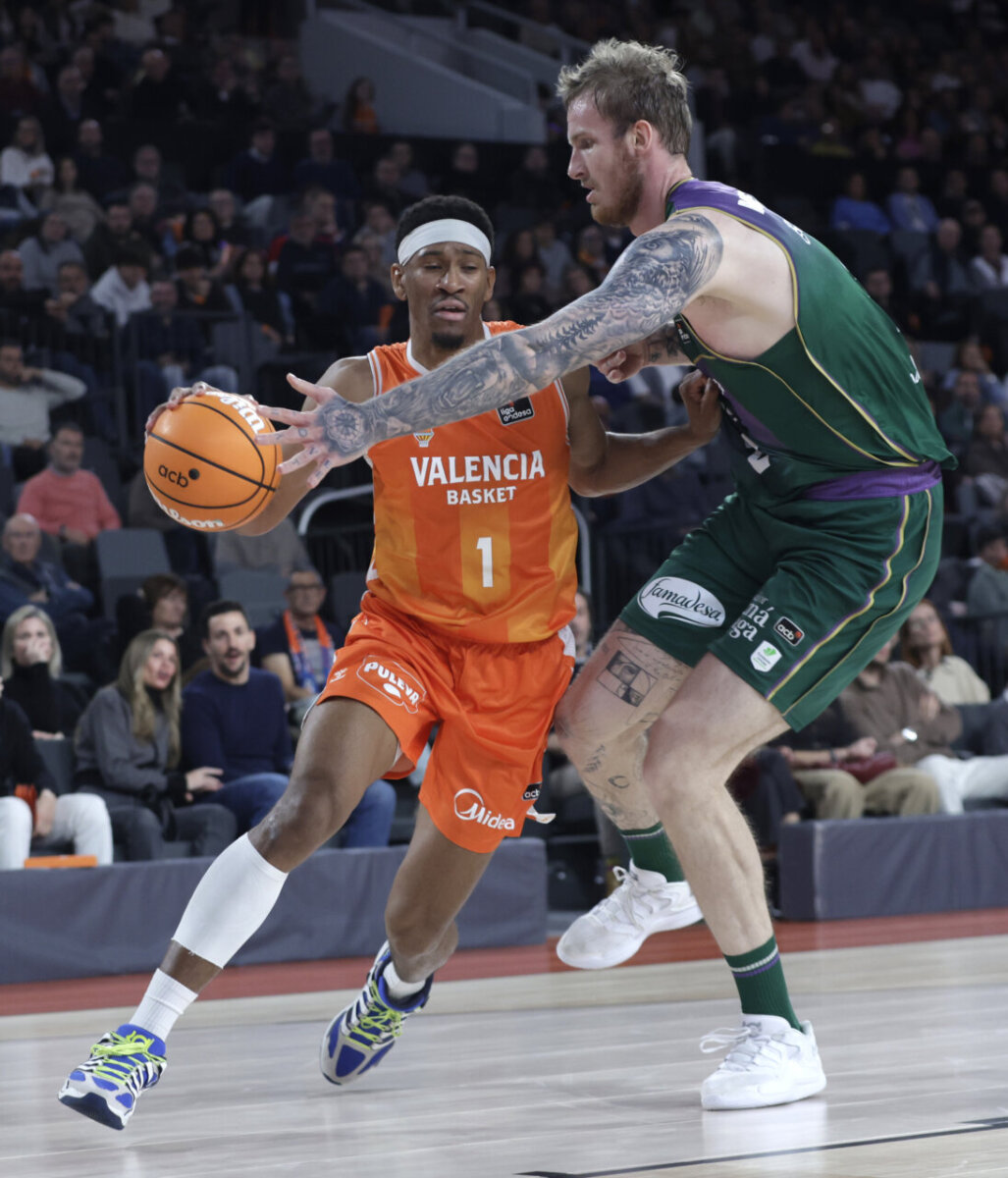 Jugador de Valencia Basket intentando driblar ante un oponente de Unicaja.