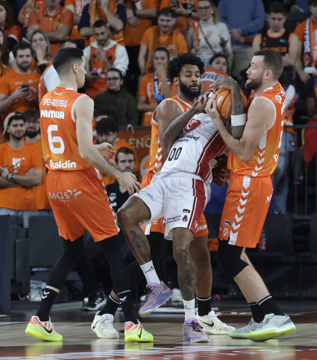 Jugadores de Valencia Basket y Casademont Zaragoza luchando por el balón en un partido de baloncesto.
