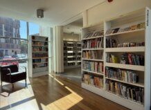 Interior de la biblioteca pública con estanterías llenas de libros y un sillón