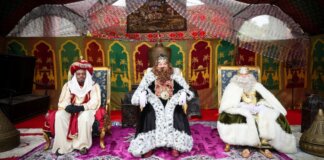 Tres Reyes Magos sentados en un campamento decorado para Navidad