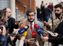 Un hombre habla a la prensa rodeado de micrófonos en un evento.