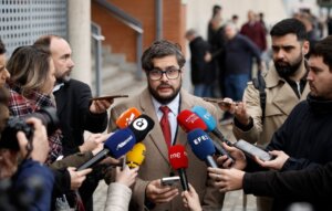 Un hombre habla a la prensa rodeado de micrófonos en un evento.