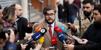 Un hombre habla a la prensa rodeado de micrófonos en un evento.