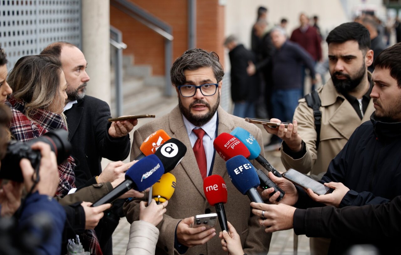 Un hombre habla a la prensa rodeado de micrófonos en un evento.