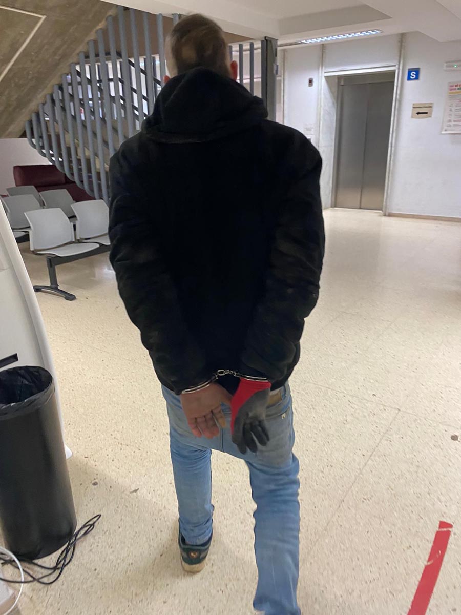 Hombre detenido con las manos esposadas en un edificio público