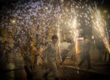 Participantes en la Entrà de la Flor con ramas de almendro en flor y fuegos artificiales.