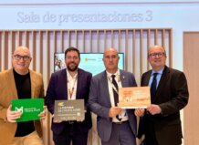 Cuatro hombres sosteniendo carteles en un evento de FITUR