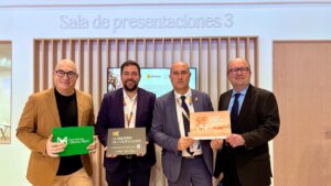 Cuatro hombres sosteniendo carteles en un evento de FITUR