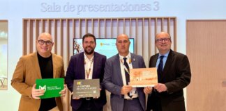 Cuatro hombres sosteniendo carteles en un evento de FITUR