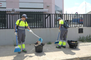 Dos trabajadores limpiando la calle en Paiporta con herramientas de jardinería