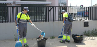 Dos trabajadores limpiando la calle en Paiporta con herramientas de jardinería