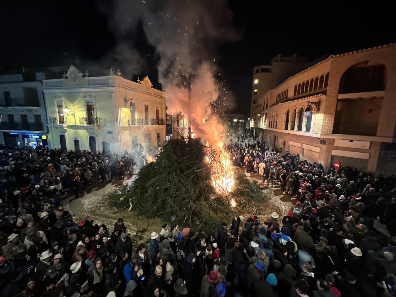 Gran hoguera durante la fiesta de Sant Antoni en Rafelbunyol con multitud de asistentes.