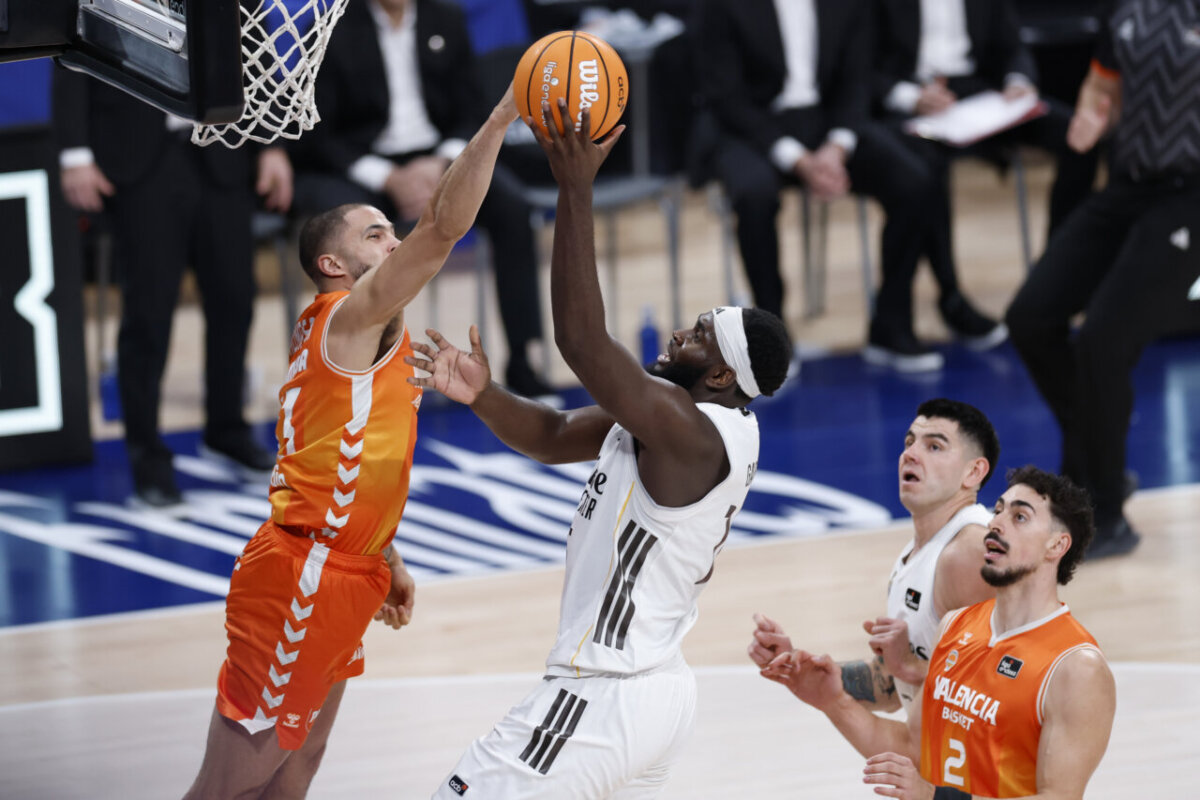 Jugadores de Valencia Basket y Real Madrid en acción durante un partido de baloncesto.