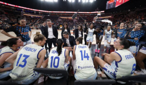 Entrenador y jugadoras de Valencia Basket discutiendo estrategia en un partido