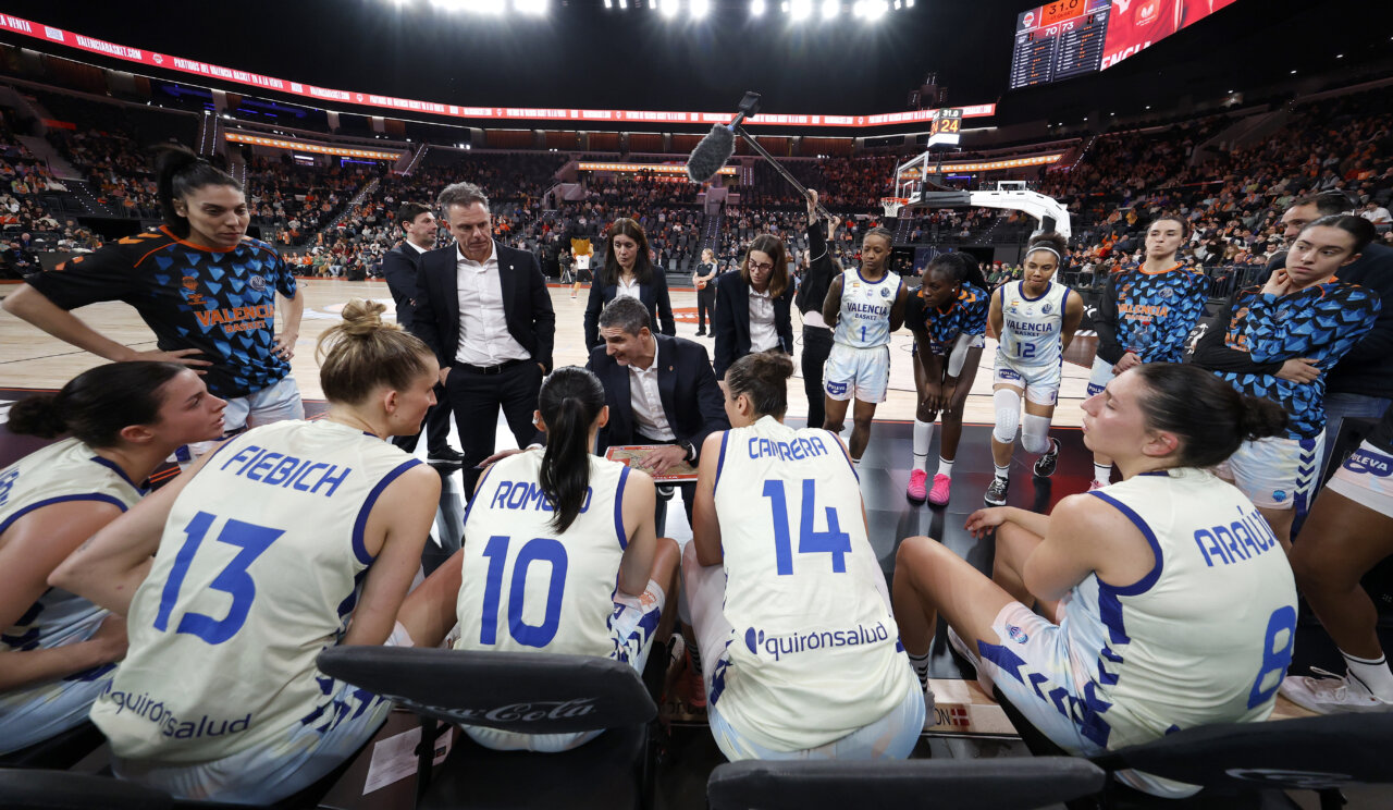 Entrenador y jugadoras de Valencia Basket discutiendo estrategia en un partido
