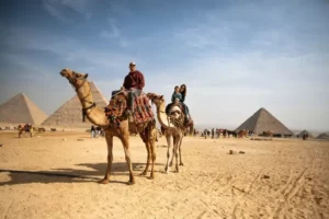 Turistas montando camellos frente a las pirámides de Egipto