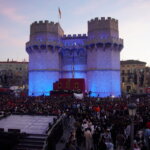 Multitud de personas en la Cridida en Valencia frente a un castillo iluminado.