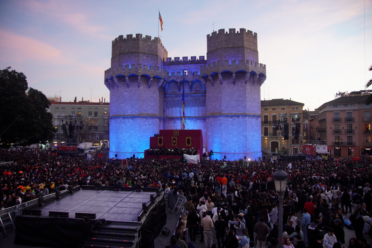Multitud de personas en la Cridida en Valencia frente a un castillo iluminado.