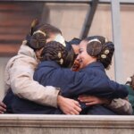 Grupo de mujeres abrazándose con trajes tradicionales y peinados elaborados