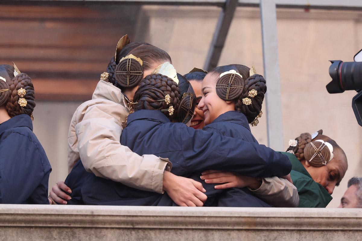 Grupo de mujeres abrazándose con trajes tradicionales y peinados elaborados