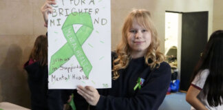 Estudiante sosteniendo cartel sobre salud mental con cinta verde