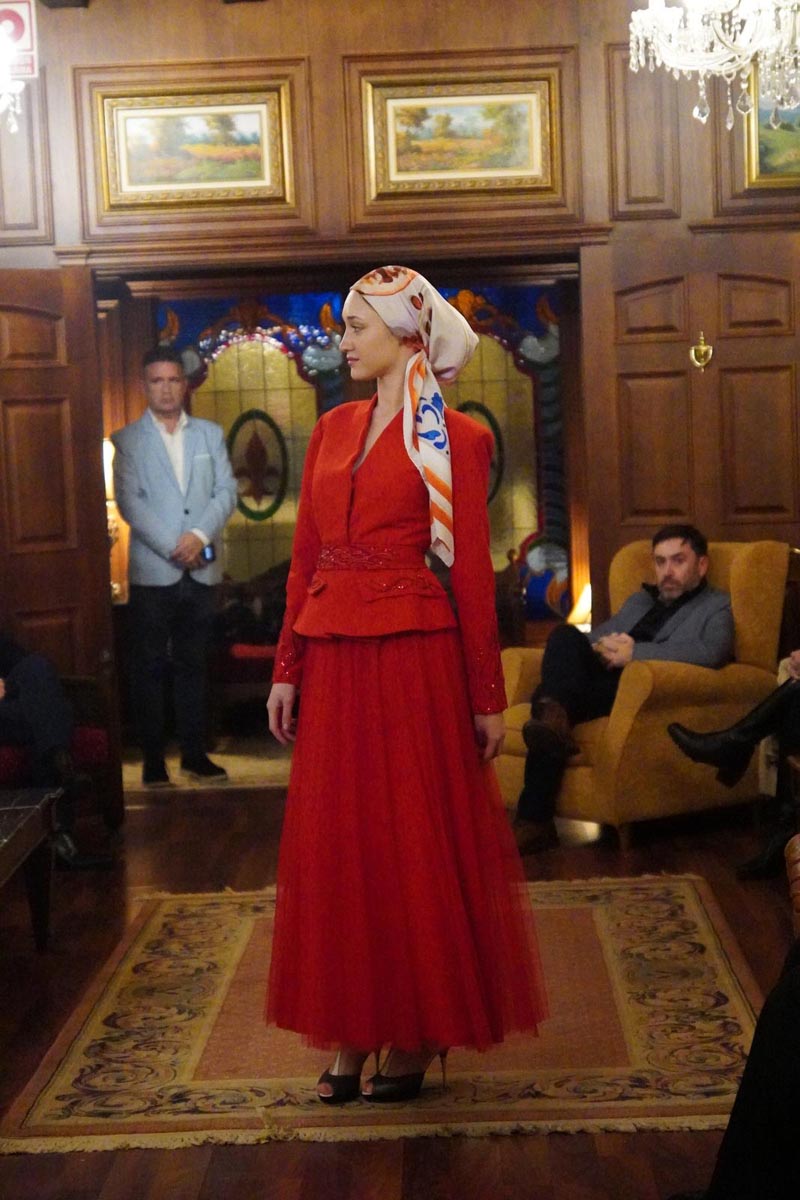 Modelo con vestido rojo y pañuelo en un evento cultural sobre reintegración social
