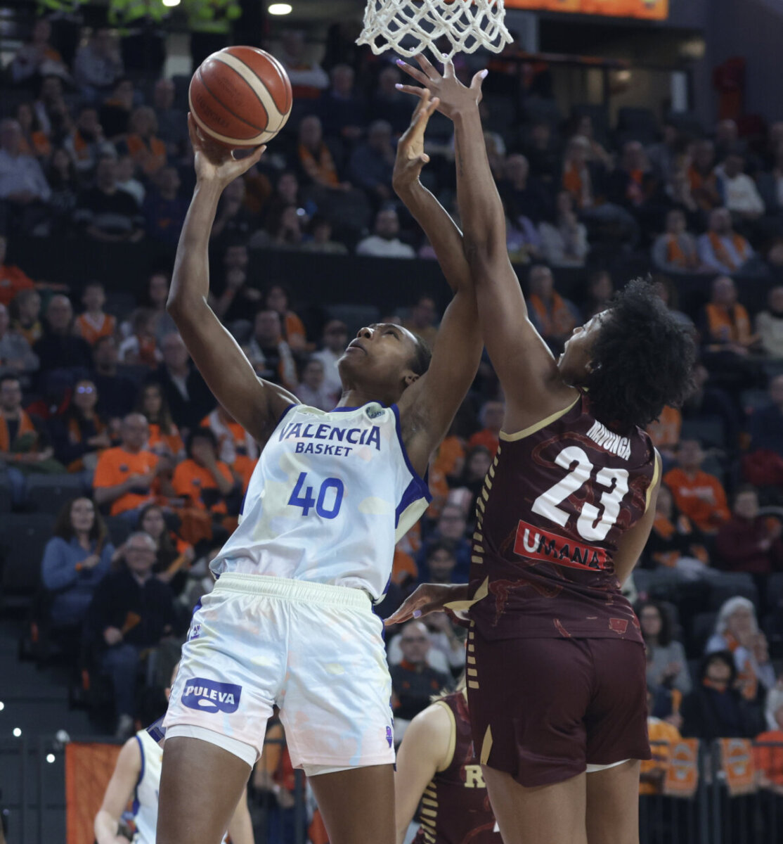Jugadora de Valencia Basket intentando anotar bajo presión en un partido de baloncesto.
