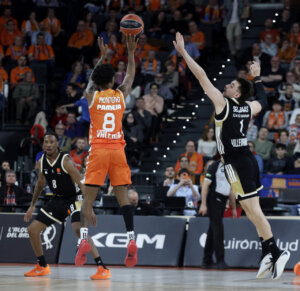 Jugador de Valencia Basket lanzando a canasta durante un partido emocionante.