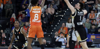 Jugador de Valencia Basket lanzando a canasta durante un partido emocionante.