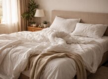 Cama con sábanas blancas y almohadas en un dormitorio acogedor