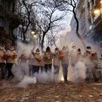 Grupo de personas en la calle durante una celebración con humo y luces