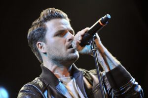 Dani Martín cantando en un concierto con micrófono en mano