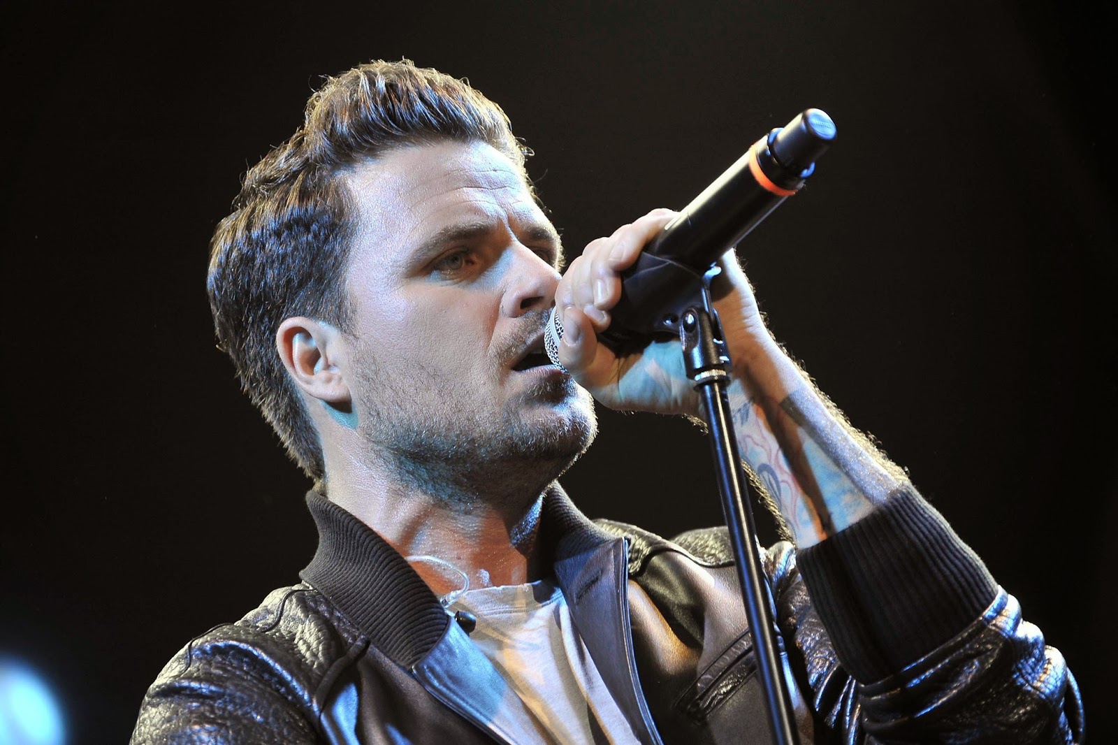 Dani Martín cantando en un concierto con micrófono en mano