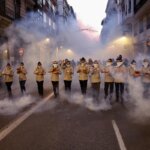 Grupo de personas en un desfile con humo en la calle