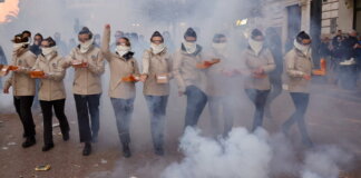 Grupo de personas en un desfile con niebla y cajas en las manos